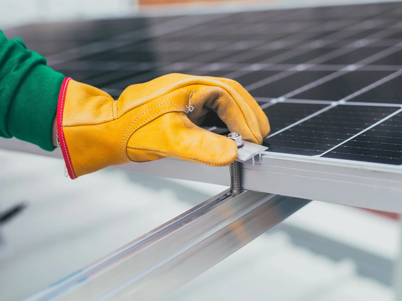 Gloved hand tightening a solar panel mounting clamp