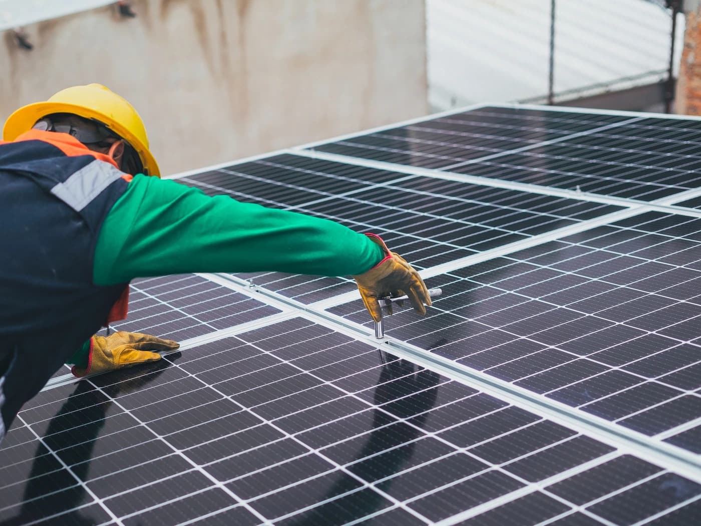 Installer in a hard hat fixing solar panels to a roof