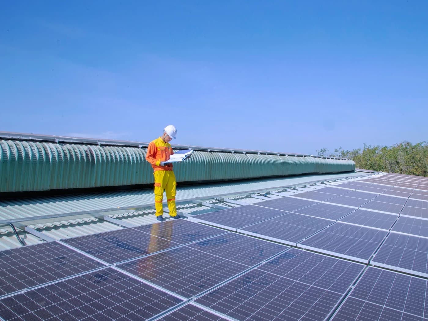 Technician with a clipboard inspecting a rooftop solar array